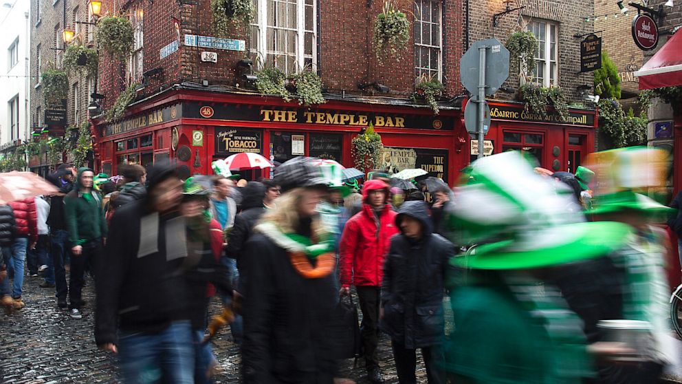 Pedestrians carrying umbrellas and wearing St. Patrick's day hats and scarves move past the Temple Bar public house in Dublin, Ireland, March 17, 2013. 