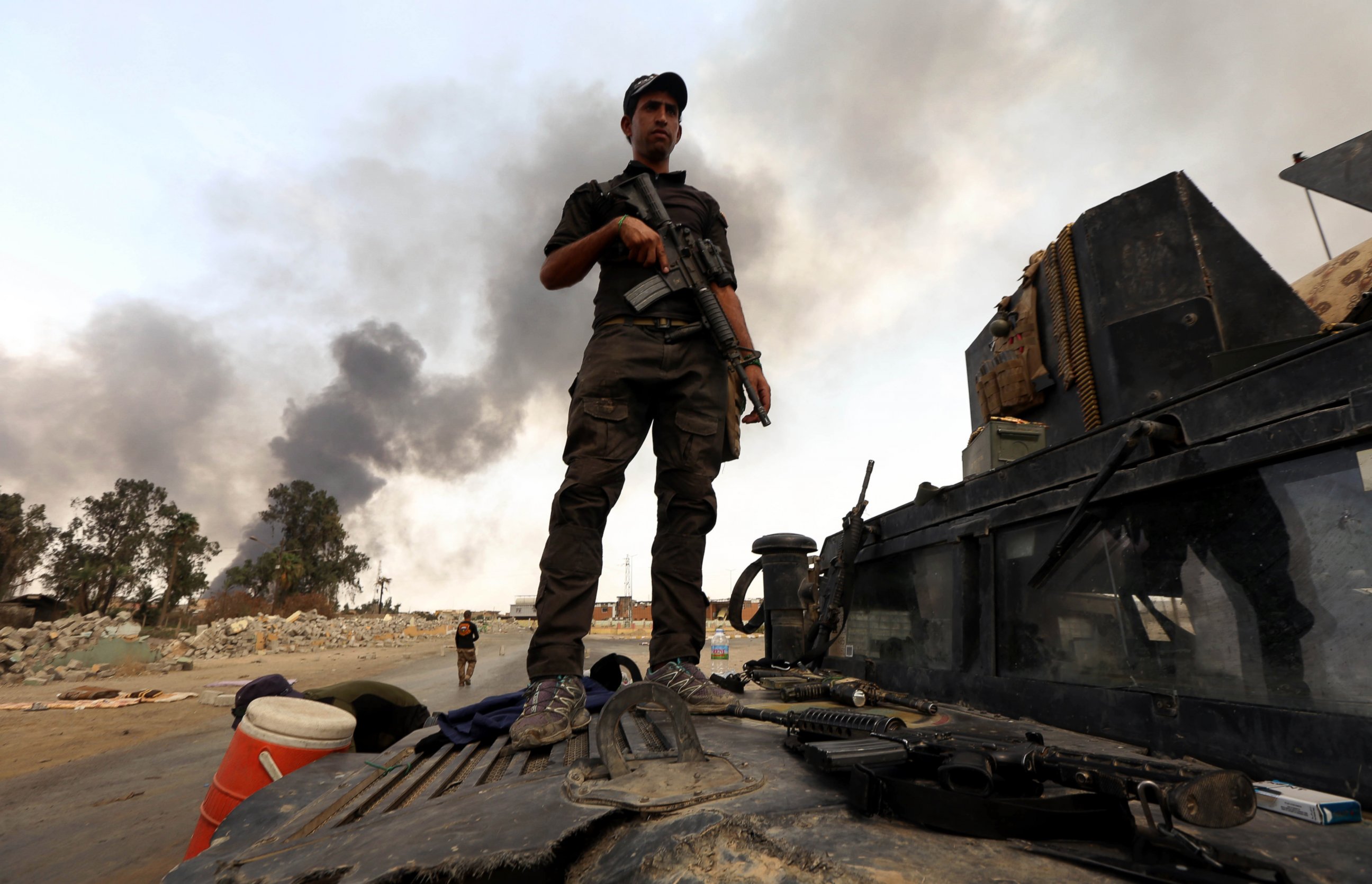 PHOTO: A member of the Iraqi government forces stands on a military vehicle as smoke billows from oil wells, set ablaze by Islamic State (IS) group militants before fleeing the oil-producing region of Qayyarah, Aug. 30, 2016. 
