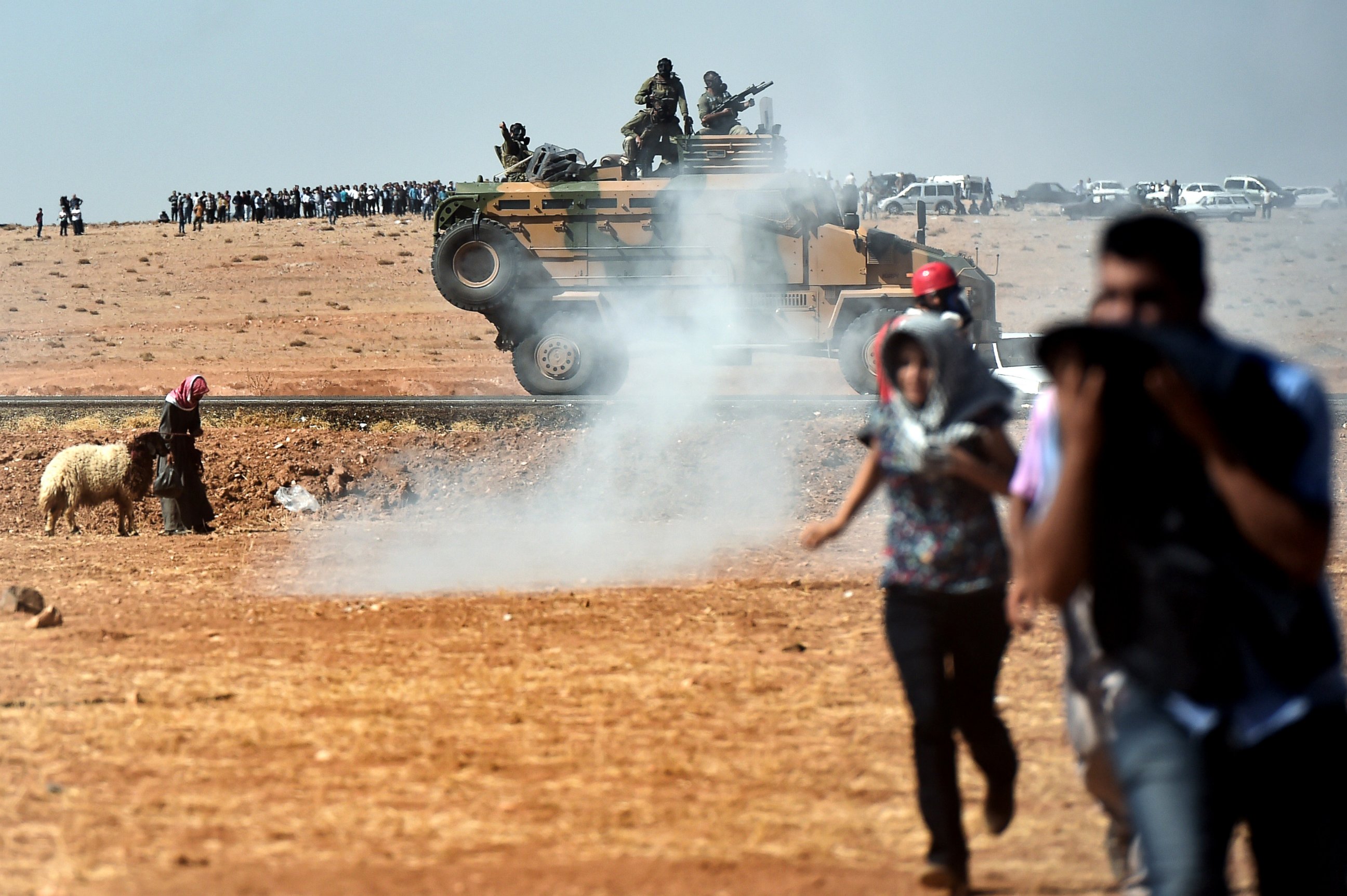 PHOTO: Kurdish people run away from tear gas as Turkish army tries to remove them from the Turkish-Syrian border area near the Syrian town known as Kobani by the Kurds, in the southeastern town of Suruc, Turkey, Oct. 7, 2014.