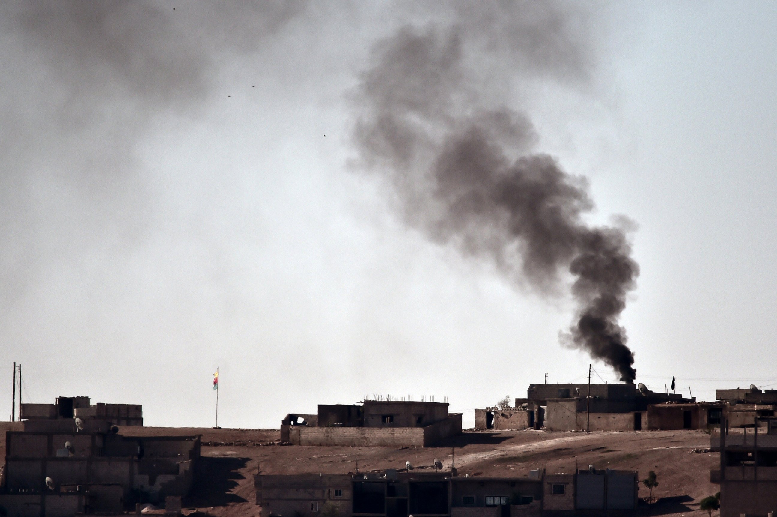 PHOTO: Smoke rises from the central part of the Syrian town of Ain al-Arab, known as Kobani by the Kurds, as seen from the Turkish-Syrian border, as a Kurdish flag waves during heavy fighting, in the southeastern town of Suruc, Turkey, Oct. 7, 2014.