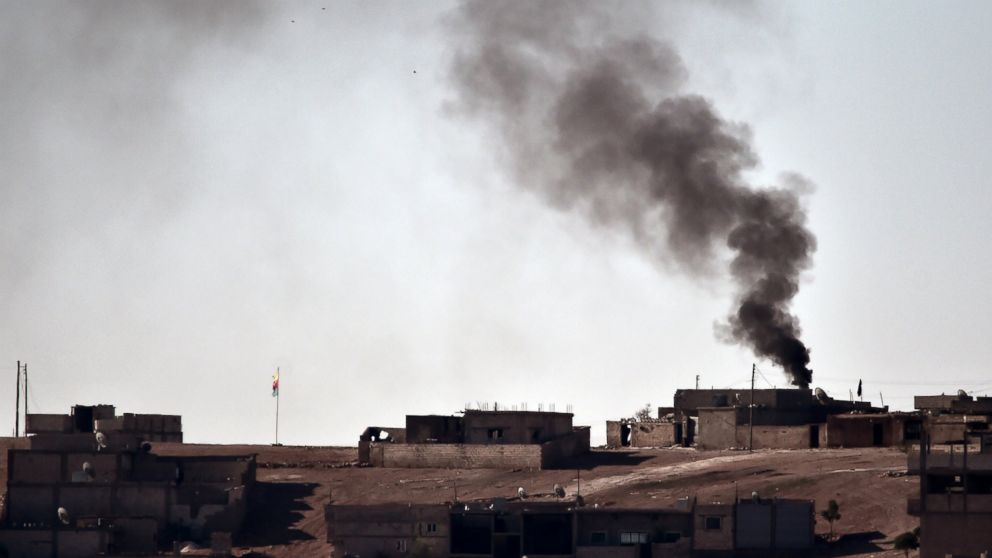 PHOTO: Smoke rises from the central part of the Syrian town of Ain al-Arab, known as Kobani by the Kurds, as seen from the Turkish-Syrian border, as a Kurdish flag waves during heavy fighting, in the southeastern town of Suruc, Turkey, Oct. 7, 2014.