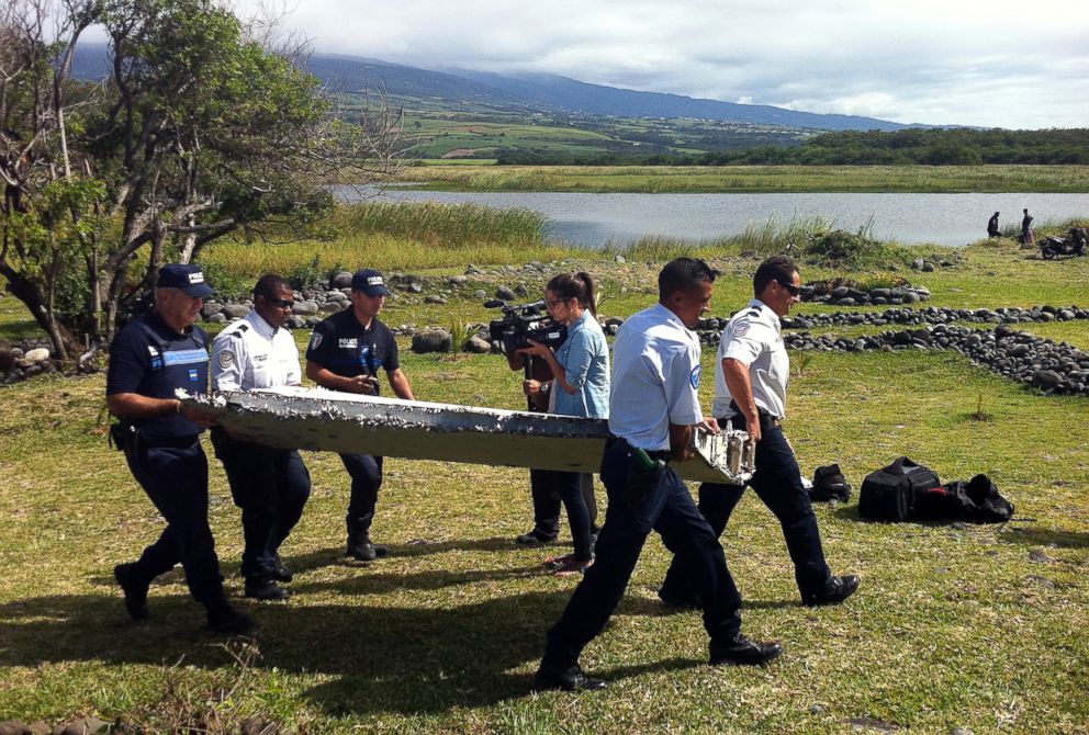 PHOTO:Police carry a piece of debris from an unidentified aircraft found in the coastal area of Saint-Andre de la Reunion, in the east of the French Indian Ocean island of La Reunion, July 29, 2015.  