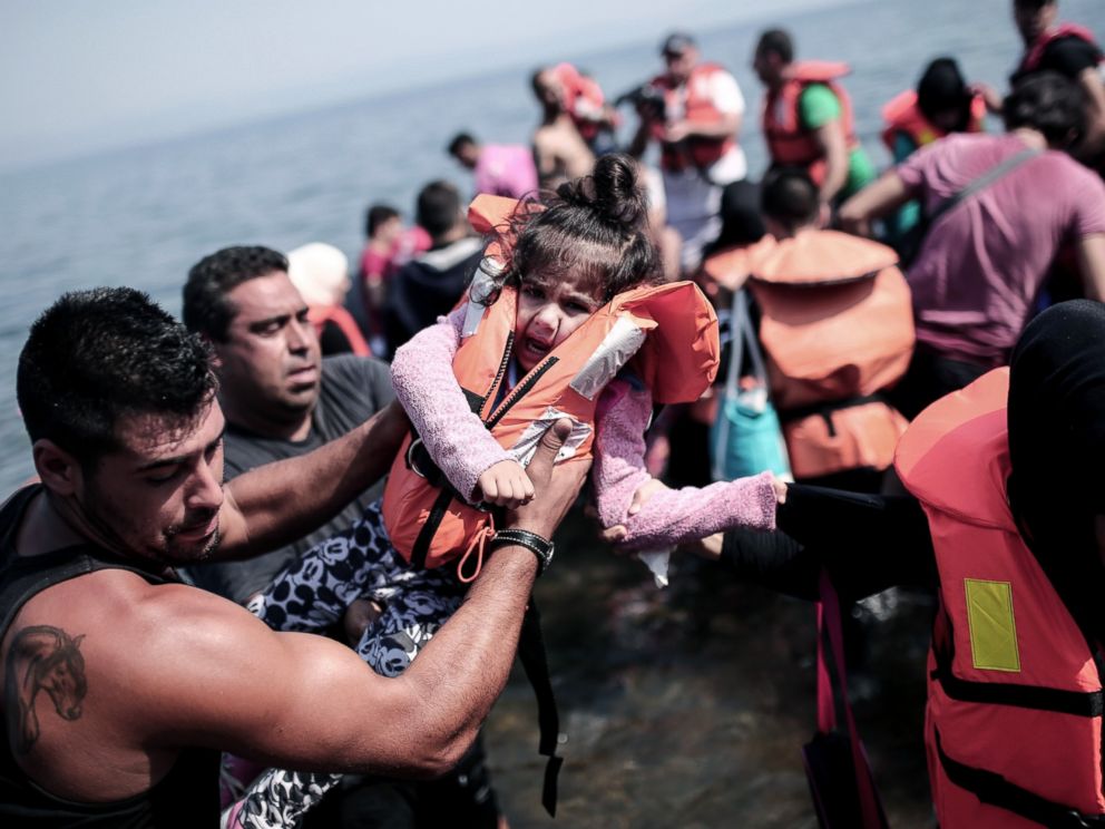 PHOTO: A refugee carries a child as they arrive on the shores of the Greek island Lesbos in an inflatable dingy across the Aegean Sea from from Turkey, Sept. 3, 2015.