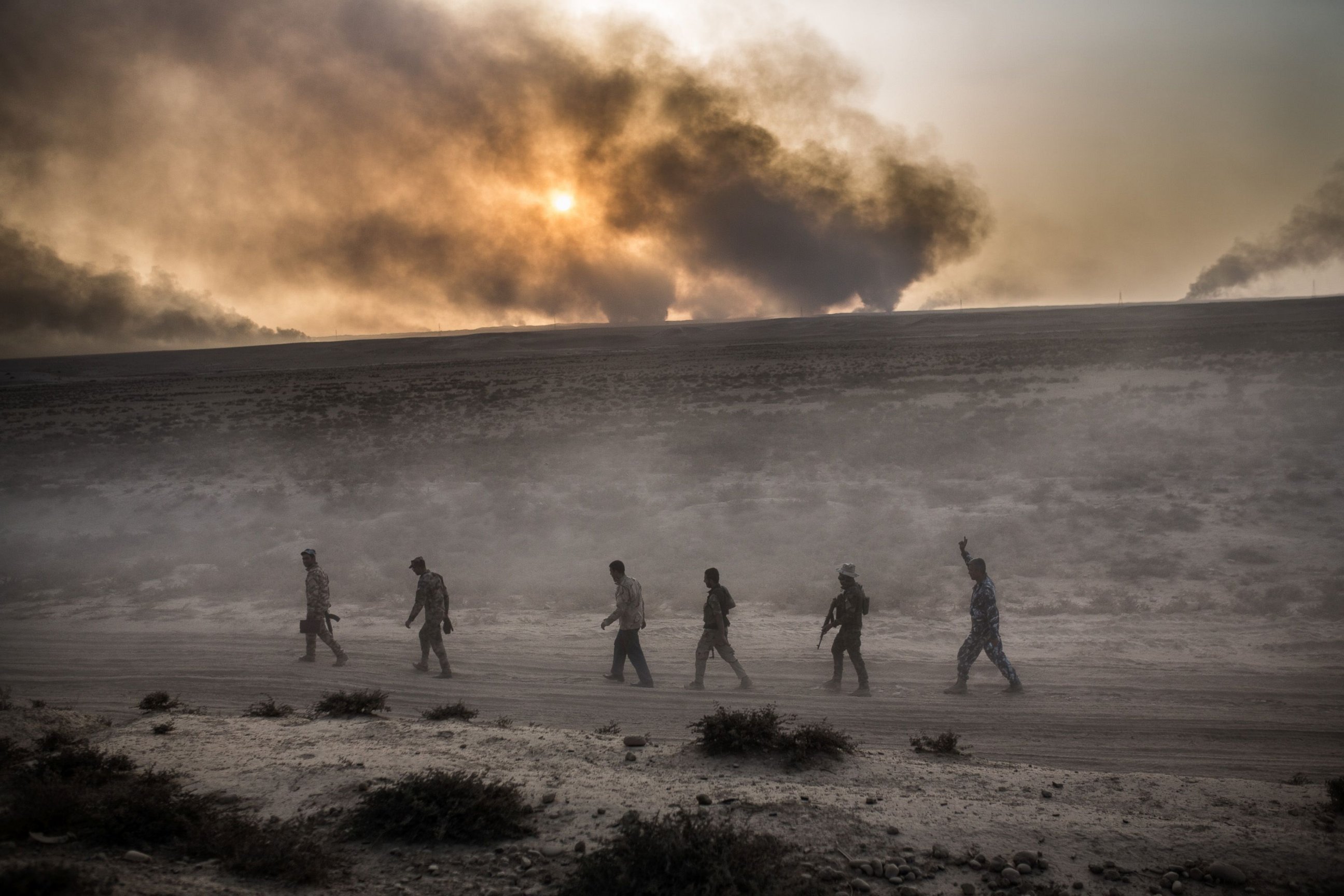 PHOTO: Iraqi soldiers walk on a road as smoke billows from the Qayyarah area, some 60 kilometers (35 miles) south of Mosul, Oct. 19, 2016, during an operation against the Islamic State to retake the main hub city.