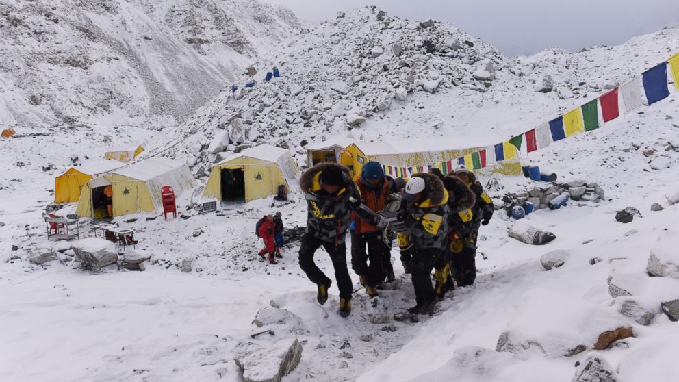 An injured person is carried by rescue members to be airlifted by rescue helicopter at Everest Base Camp on April 26, 2015, a day after an avalanche triggered by an earthquake devastated the camp. 