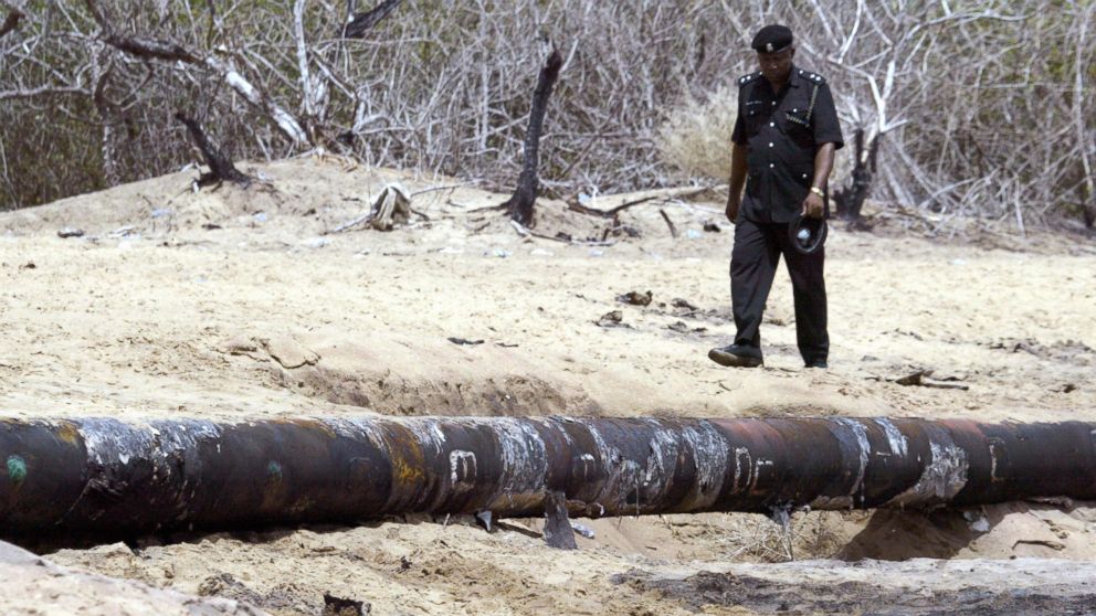 A file photo taken on May 14, 2005 shows a policeman walking past an oil pipeline that exploded after it was vandalized at Ilado beach village in Lagos, Nigeria.