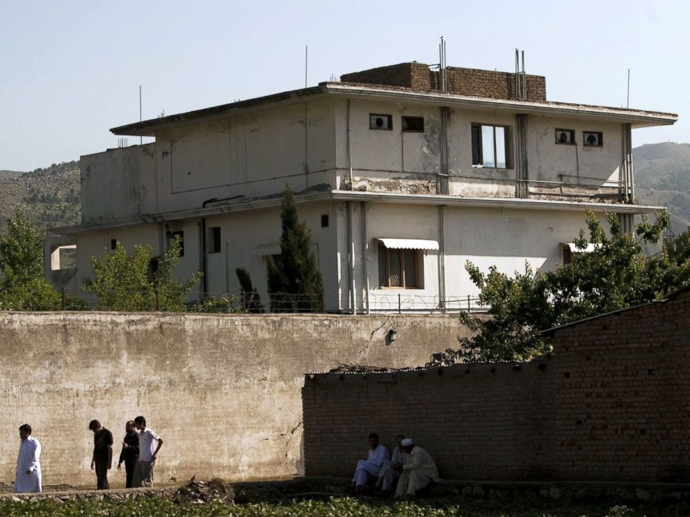PHOTO: People walk past Osama Bin Ladens compound, May 3, 2011, in Abottabad, Pakistan.
