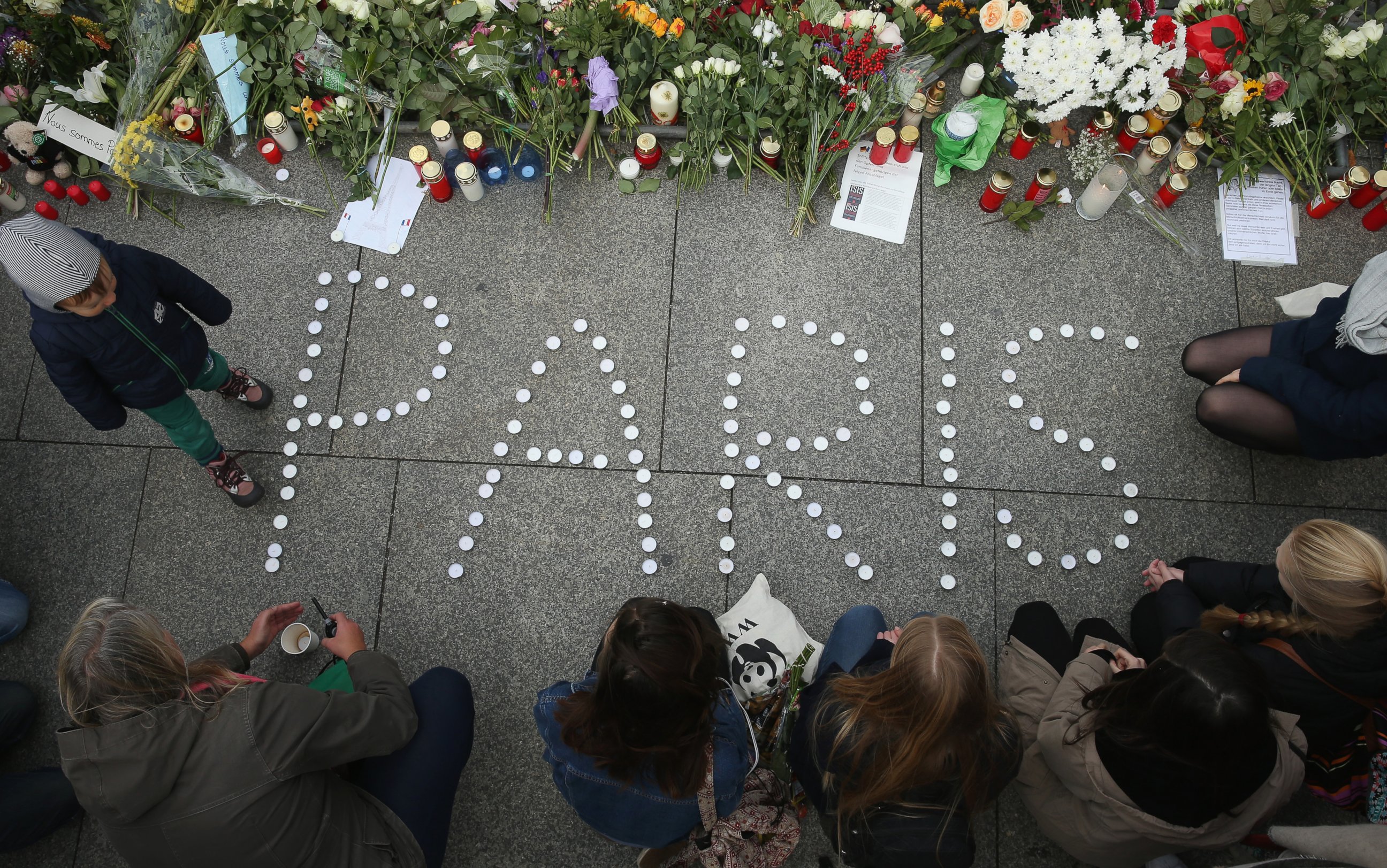 PHOTO: People finish arranging candles into the word "Paris" next to flowers and messages left at the gate of the French Embassy following the recent terror attacks in Paris, Nov. 14, 2015 in Berlin. 