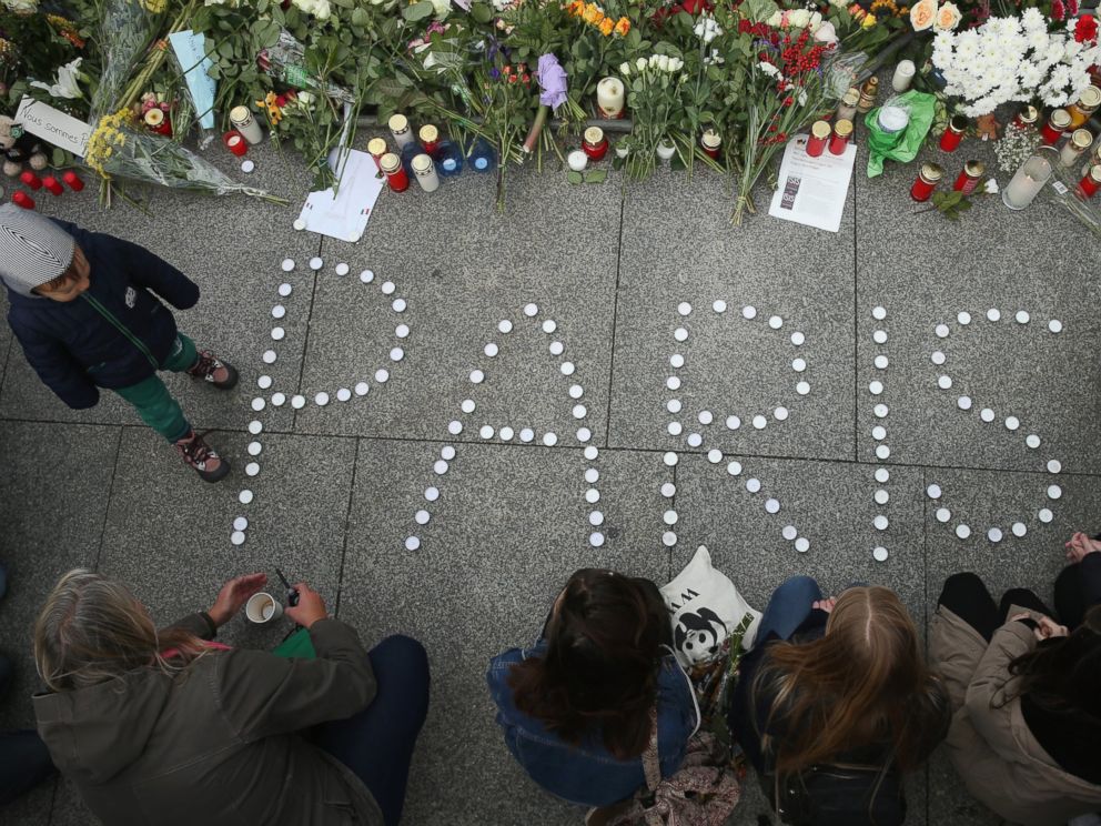 PHOTO: People finish arranging candles into the word Paris next to flowers and messages left at the gate of the French Embassy following the recent terror attacks in Paris, Nov. 14, 2015 in Berlin.