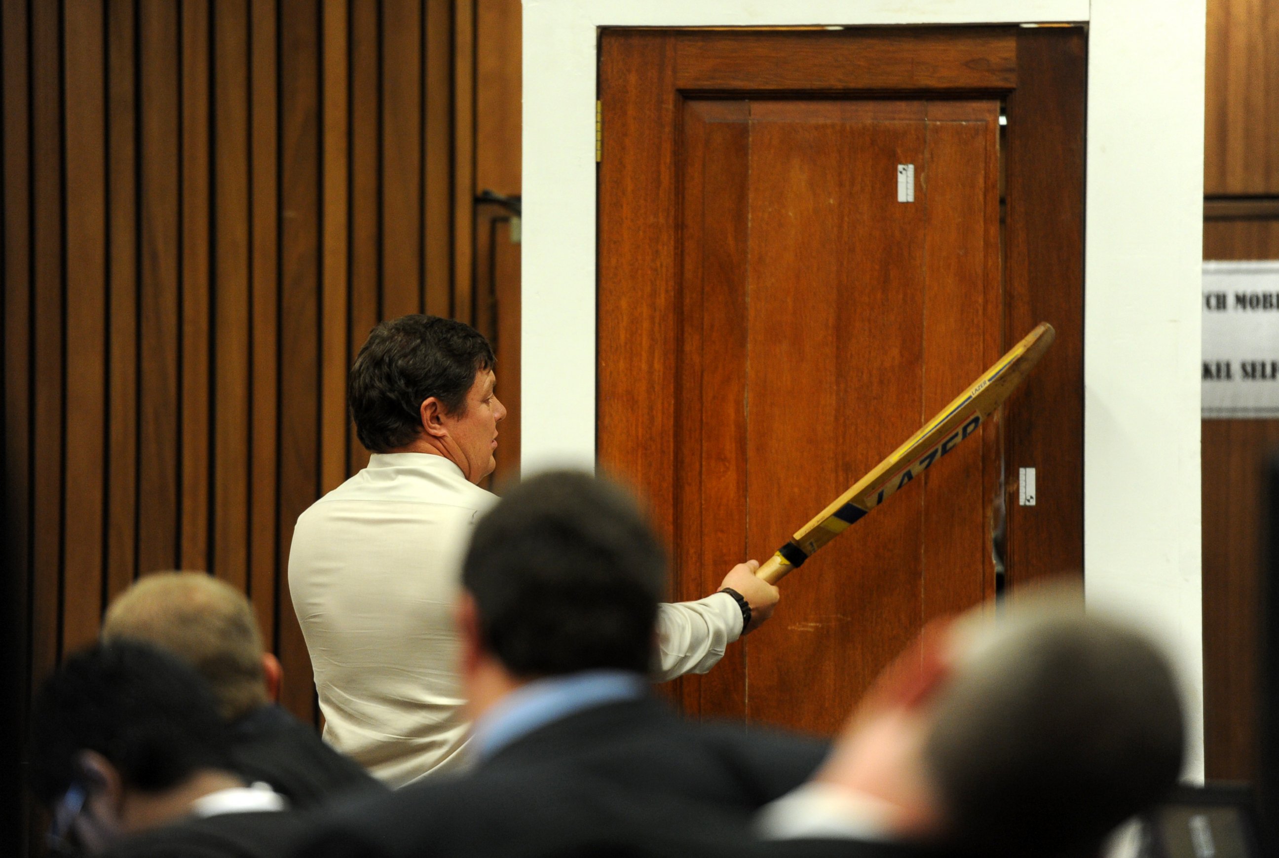 PHOTO: Forensic investigator Johannes Vermeulen takes part in the reconstruction of hitting a door with a cricket bat during the trial of Oscar Pistorius in Pretoria, South Africa on March 12, 2014.