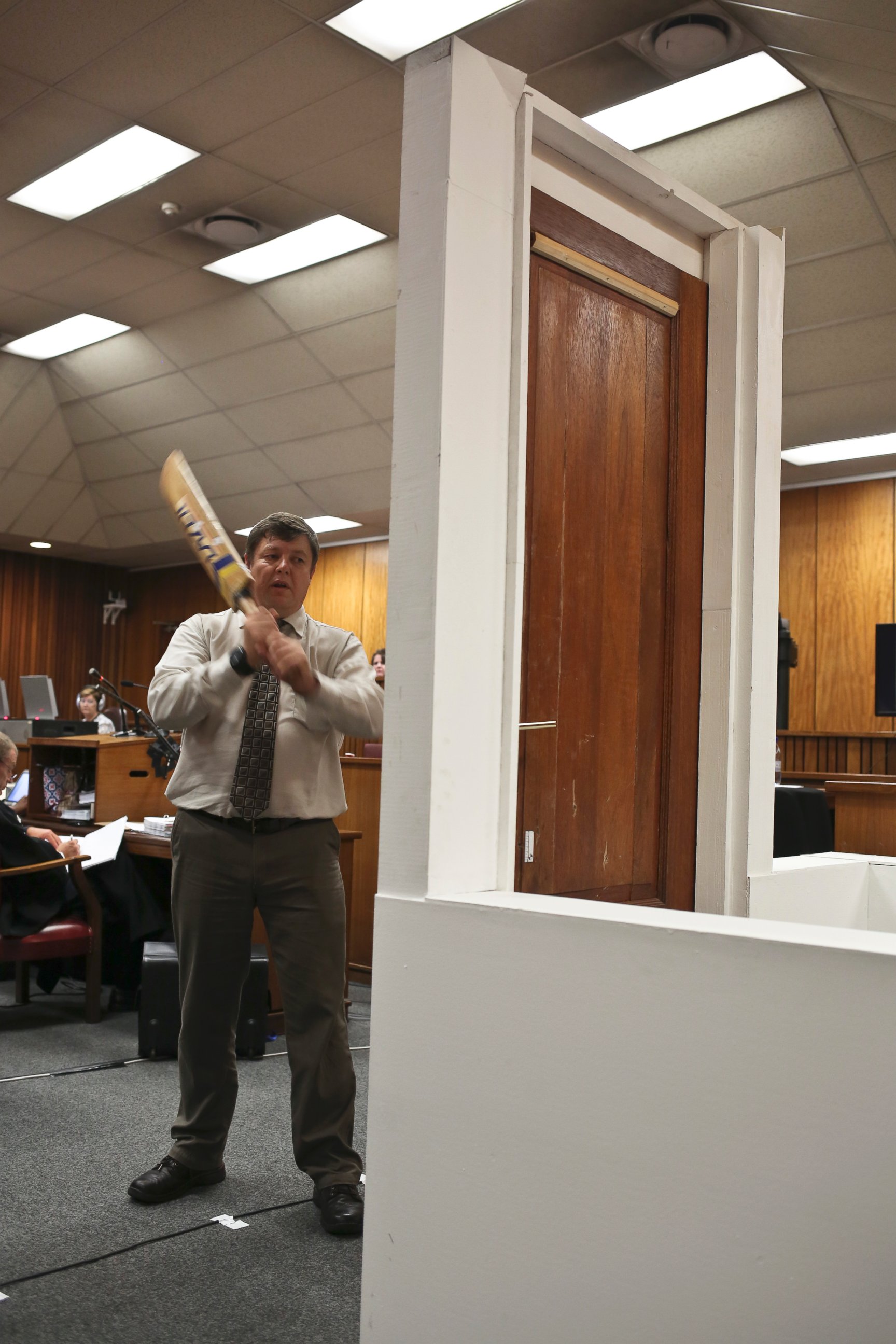 PHOTO: Forensic investigator Johannes Vermeulen takes part in the reconstruction of hitting a door with a cricket bat during the trial of Oscar Pistorius in Pretoria, South Africa on March 12, 2014. 