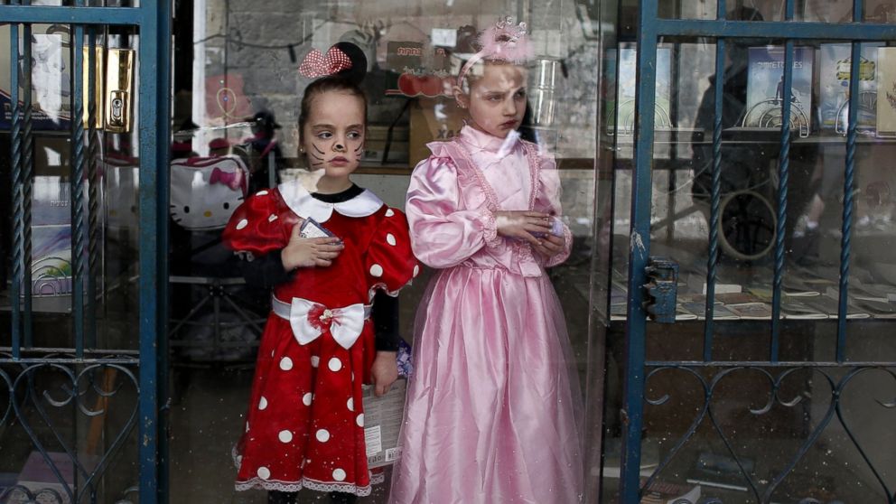 Orthodox Jewish girls look on from behind a shop's window in Jerusalem's neighborhood of Mea Sharim, on March 6, 2015 during the feast of Purim. 