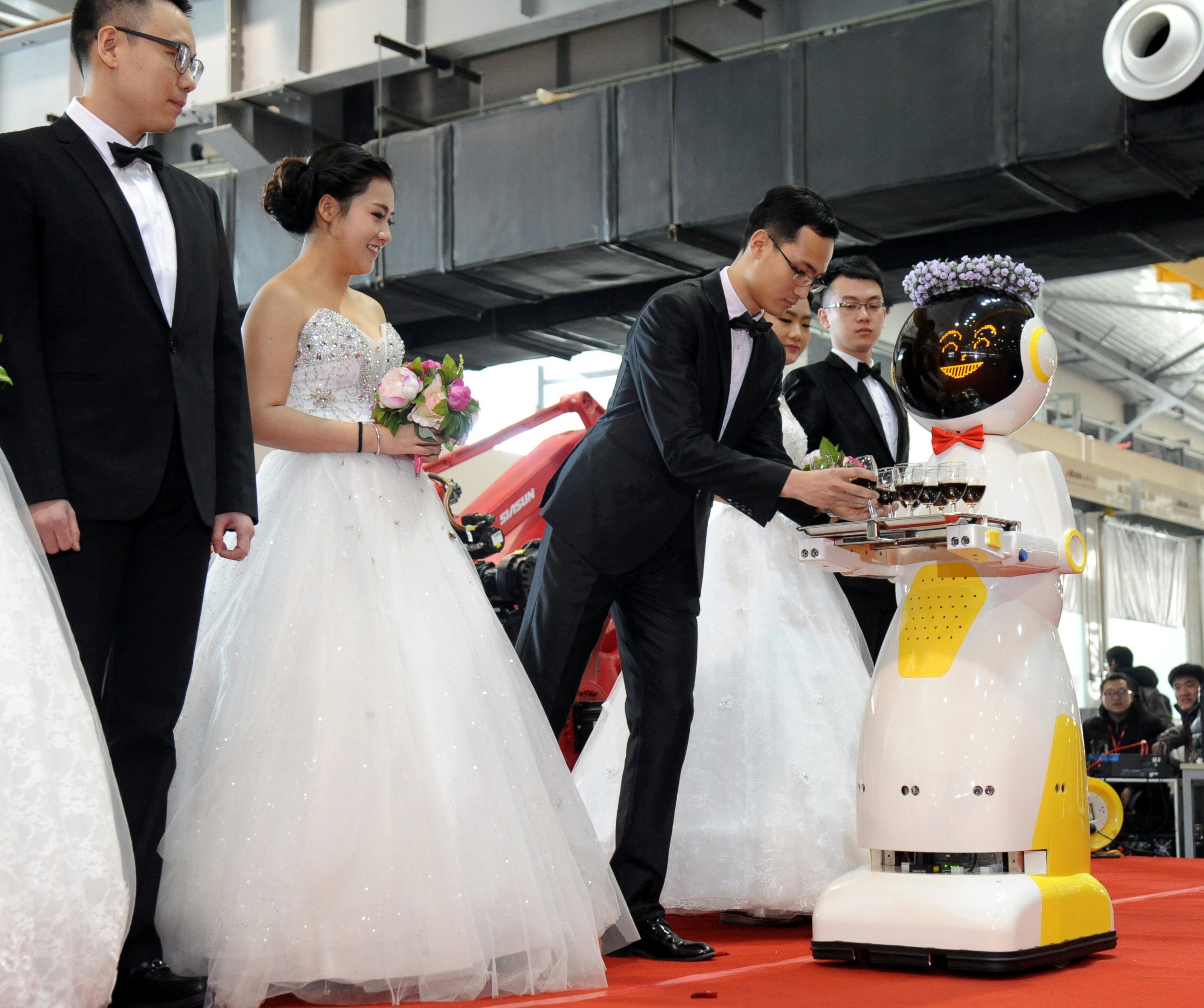 PHOTO: A service robot hands out glasses of red wine for brides and grooms during a group wedding ceremony at a robots factory, Jan. 20, 2016, in Shenyang, China.