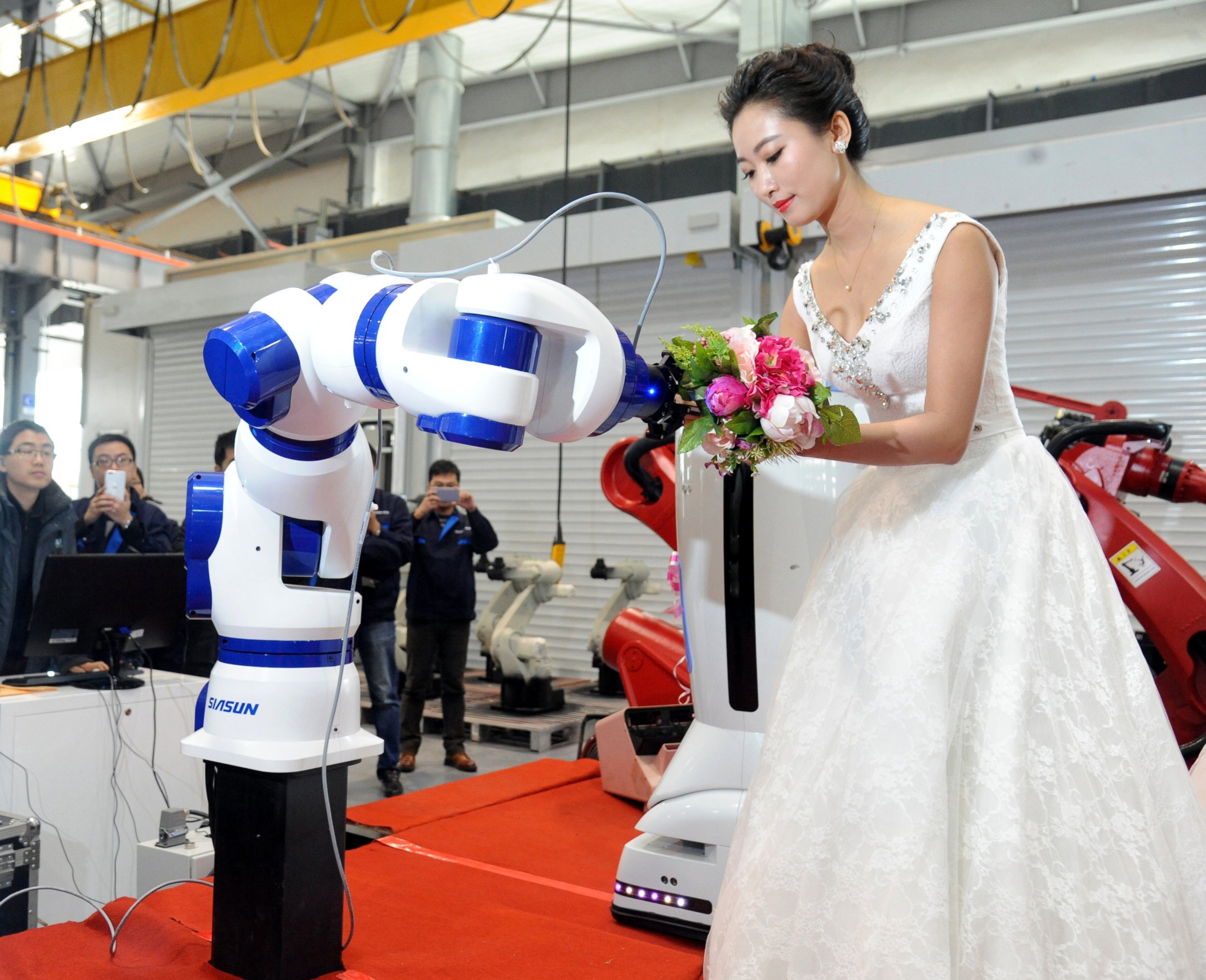 PHOTO: A bride gives the bouquet to a robot during a group wedding ceremony at a robot factory, Jan. 20, 2016, in Shenyang, China.