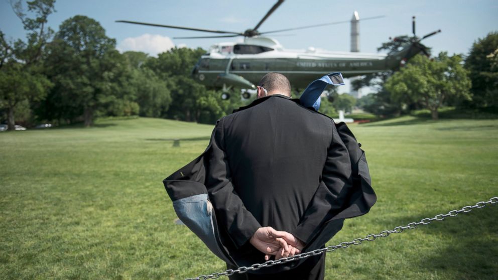 A Secret Service agent ducks rotor wash as Marine One lands on the South Lawn of the White House, May 29, 2013, in Washington.