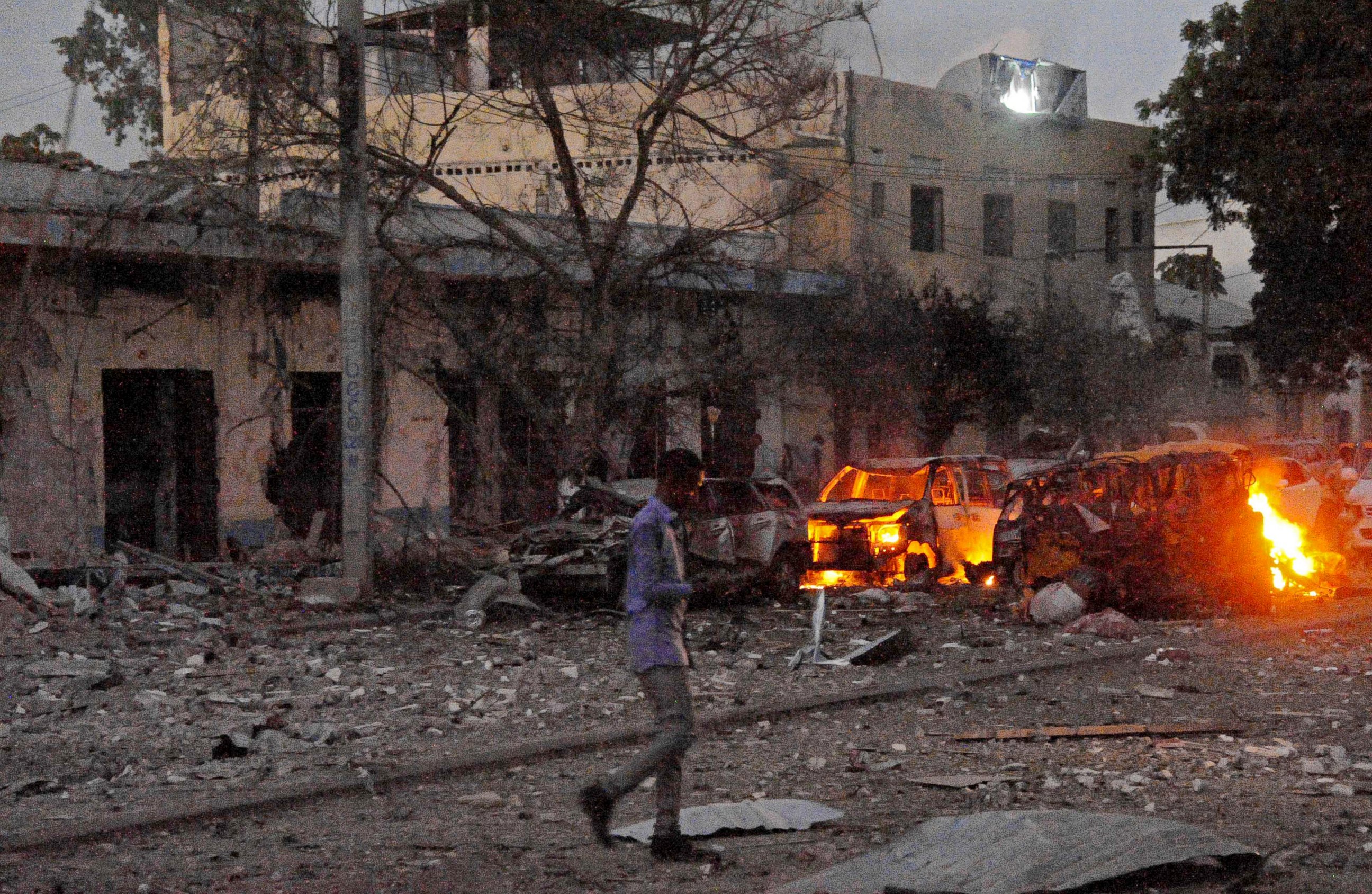 PHOTO: A man walks past the scene after a car bomb exploded, June 1, 2016, outside a Mogadishu hotel that houses several MPs, killing several people, and followed by a gun battle.