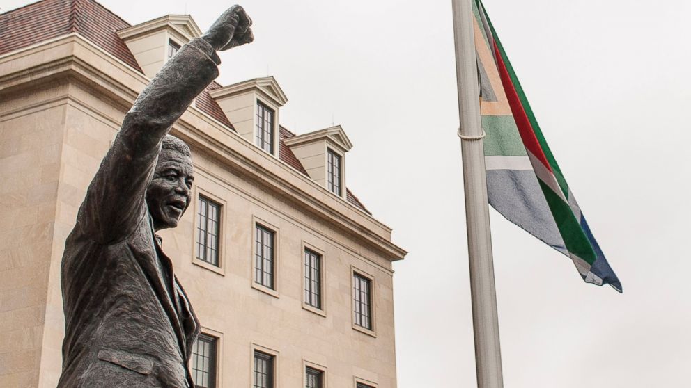 In this file photo, a flag flies near a statue of Nelson Mandela outside the South African Embassy in Washington, Dec. 6, 2013.