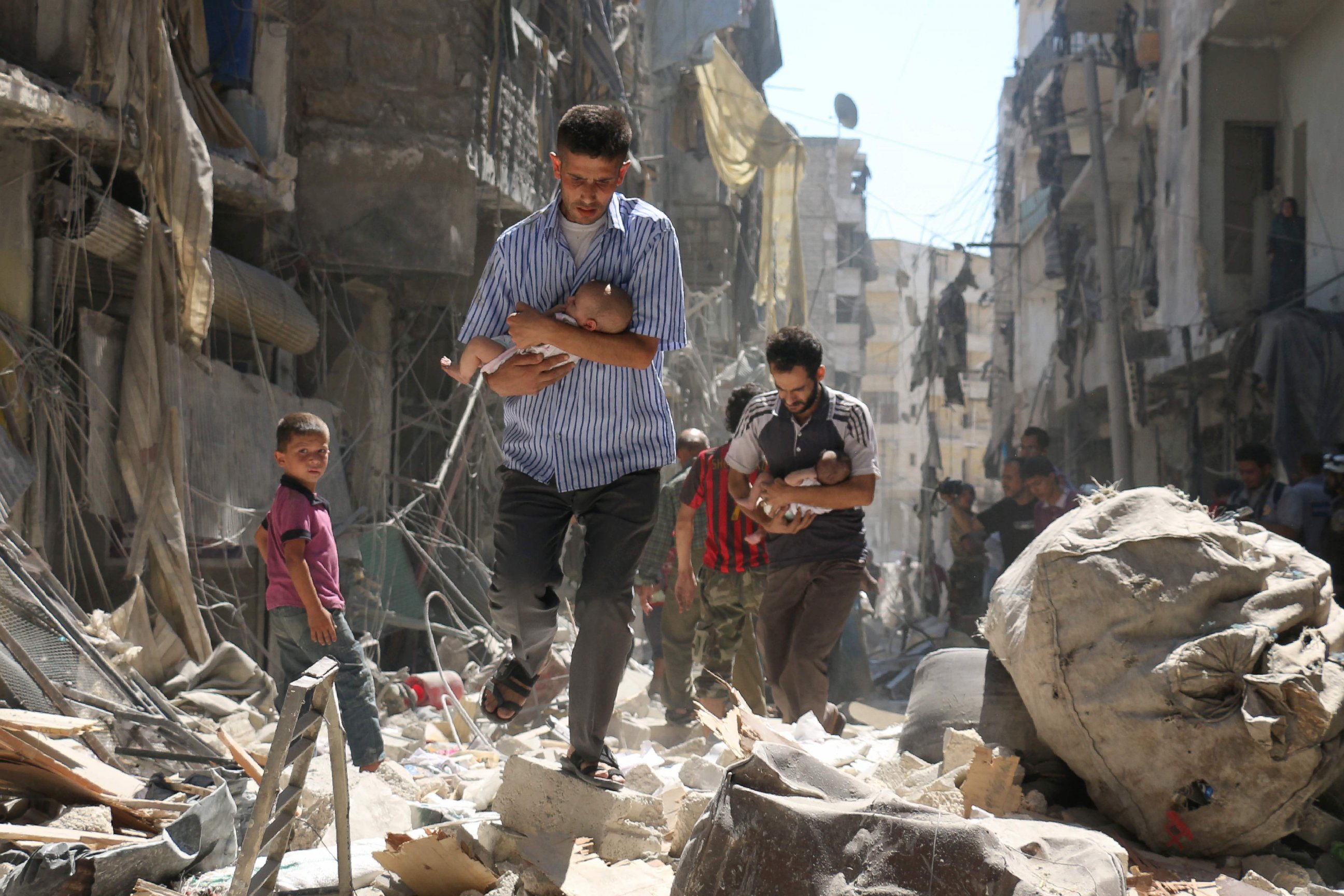 PHOTO: Syrian men carrying babies make their way through the rubble of destroyed buildings following a reported air strike on the rebel-held Salihin neighborhood of the northern city of Aleppo, Sept.  11, 2016.