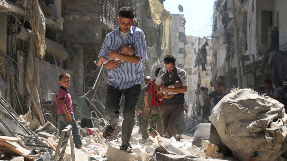 PHOTO: Syrian men carrying babies make their way through the rubble of destroyed buildings following a reported air strike on the rebel-held Salihin neighborhood of the northern city of Aleppo, Sept.  11, 2016.