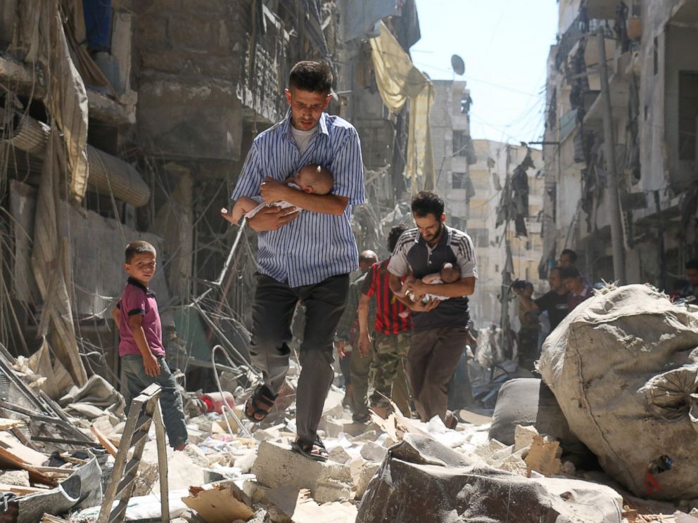 PHOTO: Syrian men carrying babies make their way through the rubble of destroyed buildings following a reported air strike on the rebel-held Salihin neighborhood of the northern city of Aleppo, Sept. 11, 2016.