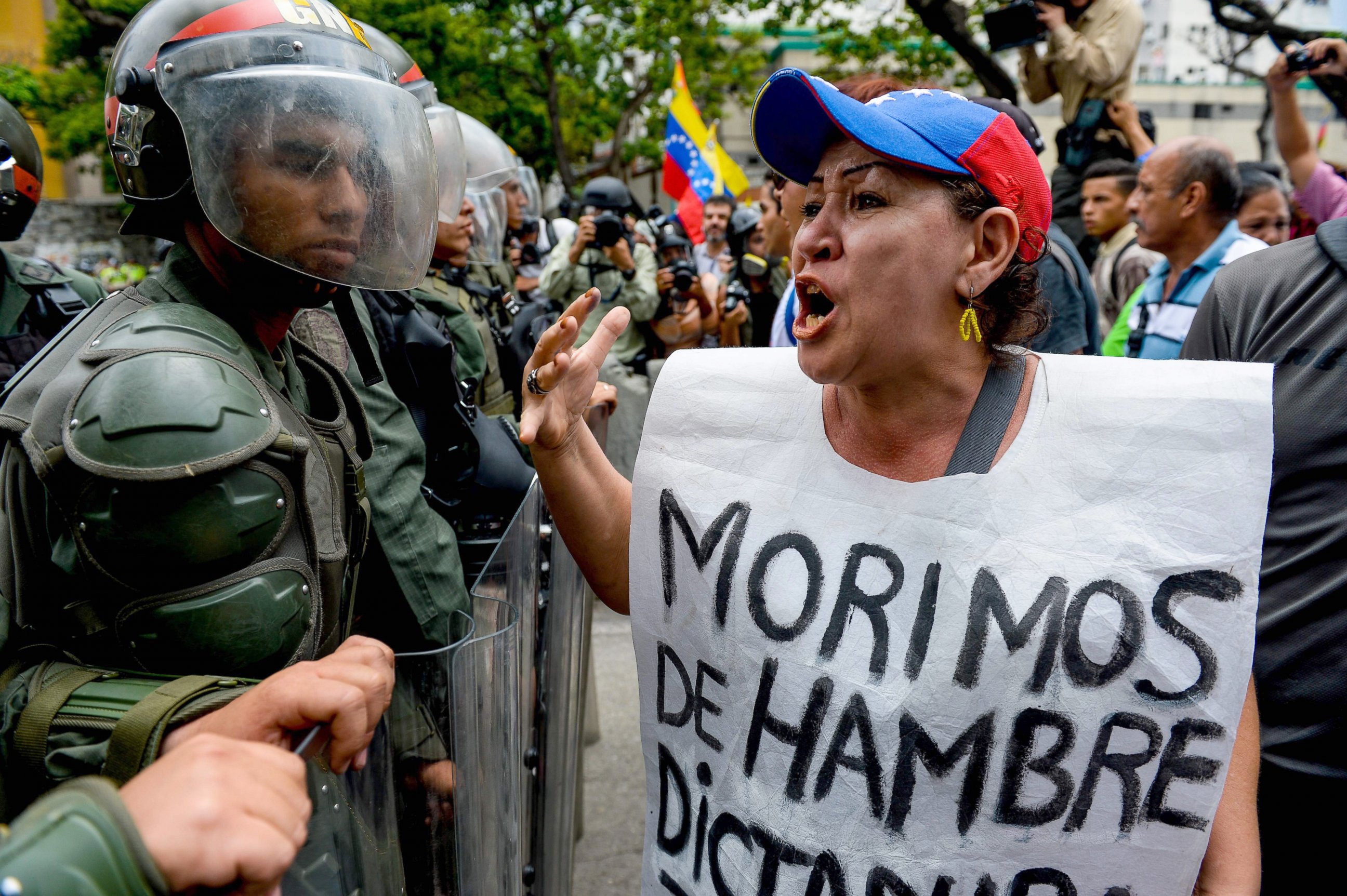 PHOTO: A woman with a sign reading "We starve" protests against new emergency powers decreed this week by President Nicolas Maduro in front of a line of riot policemen in Caracas, May 18, 2016. 