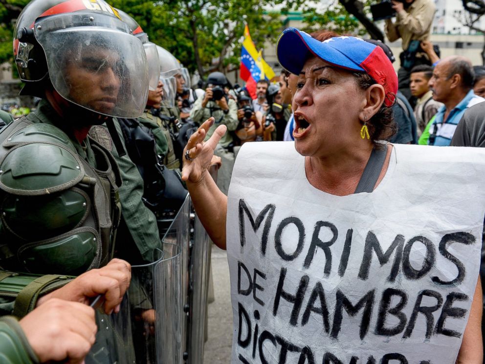 PHOTO: A woman with a sign reading We starve protests against new emergency powers decreed this week by President Nicolas Maduro in front of a line of riot policemen in Caracas, May 18, 2016.