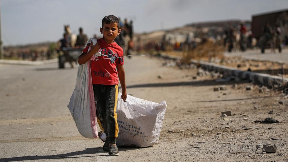 PHOTO: A Palestinian boy carries bags from a food distribution point near the Netzarim corridor in the central Gaza Strip, on Oct. 5, 2025.