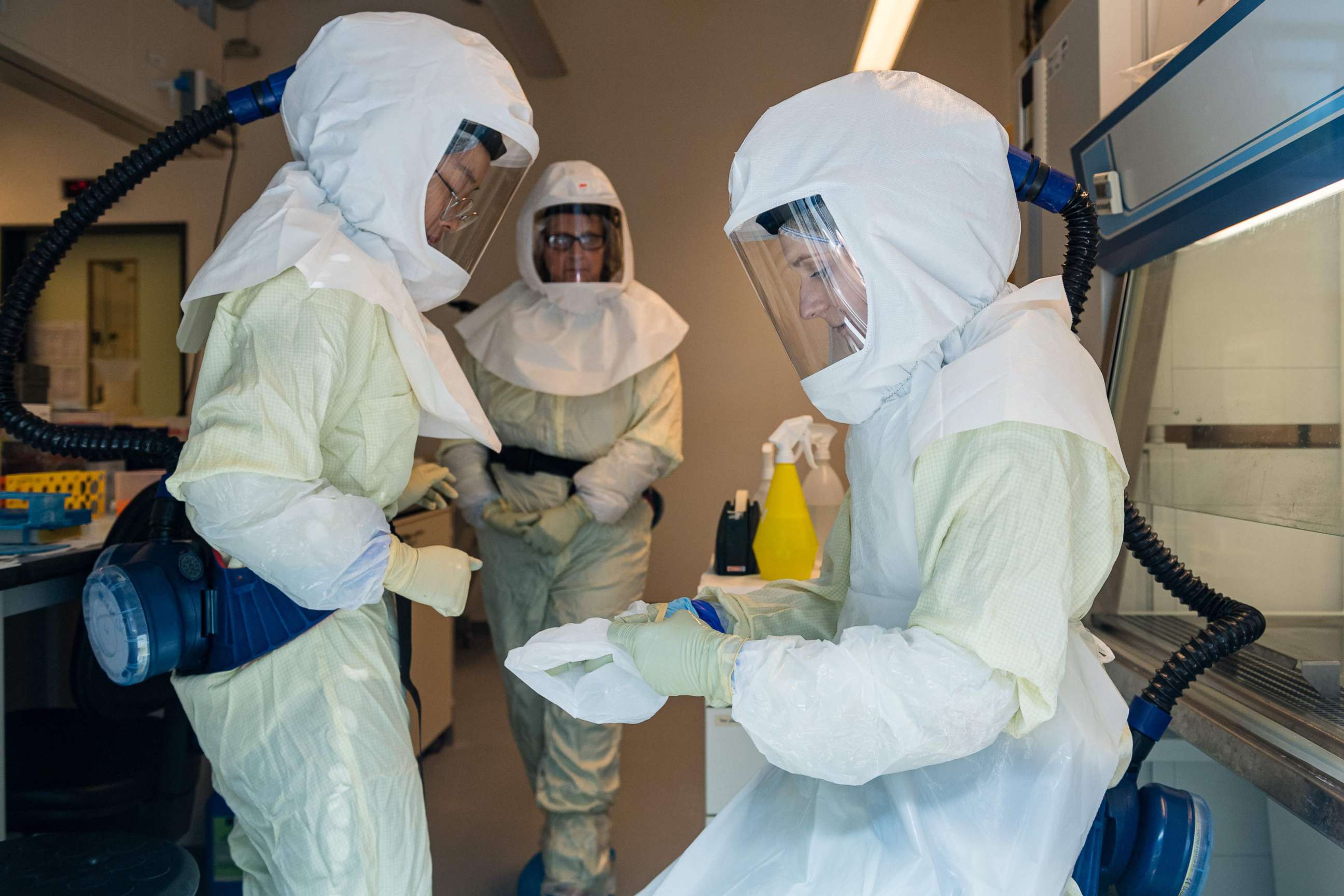 PHOTO: Picture taken through a security window shows scientists of the Helmholtz Center for Infection Research wearing special protective suits as they work in a high security laboratory at the center in Braunschweig, northern Germany, on May 8, 2020. 