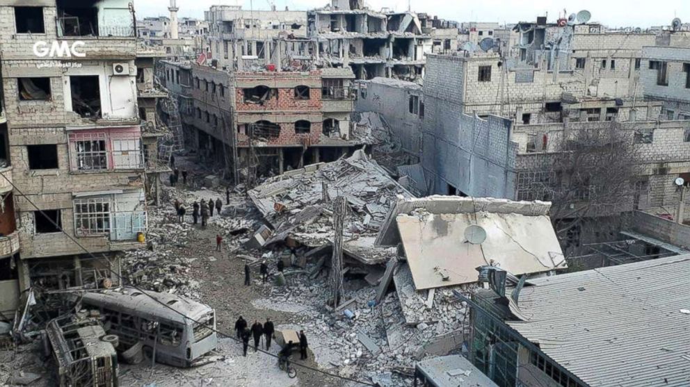 PHOTO: Syrians gather between destroyed buildings after an attack of airstrikes and shelling by Syrian government forces, in Ghouta, a suburb of Damascus, Syria on Feb. 22, 2018. 