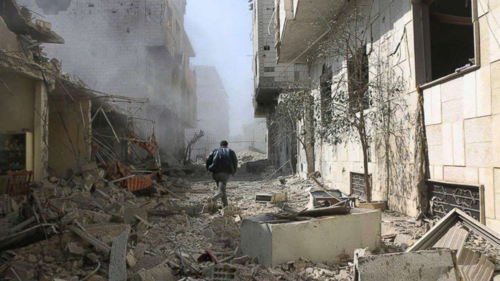 A Syrian man runs between destroyed buildings which were attacked during airstrikes and shelling by Syrian government forces, in Ghouta, a suburb of Damascus, Syria, Feb. 22, 2018.

