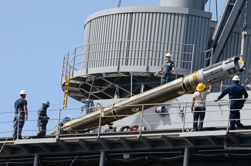 PHOTO: Sailors and civilian mariners assigned to the submarine tender USS Frank Cable (AS 40) raise a Tomahawk cruise missile before loading it onto a submarine.