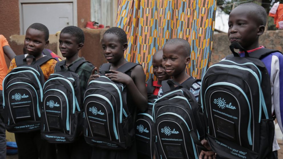 PHOTO: Local children pose with solar panel equipped backpacks from the Soular Backpack that launched in 2015 to allow children take control of their education, Katwe, Uganda.  
