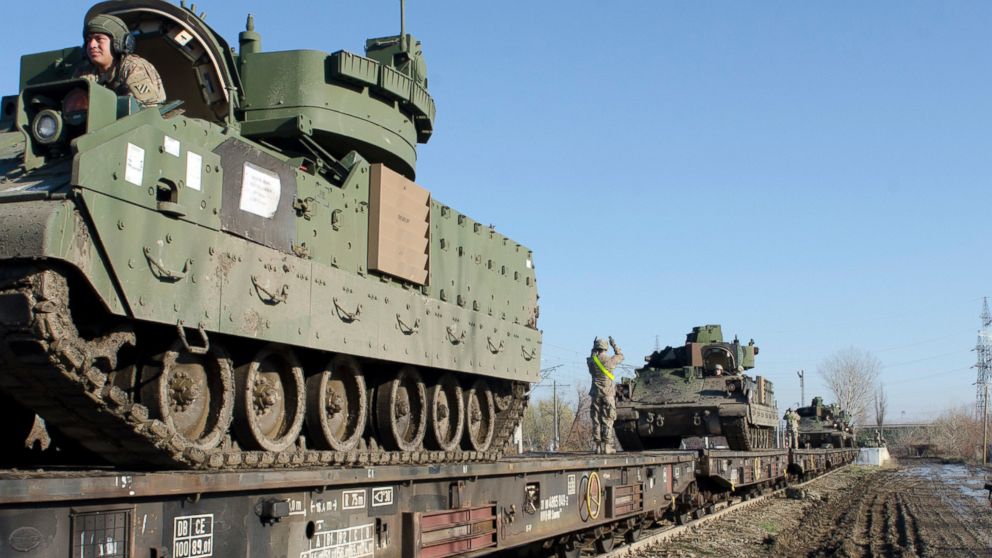 Soldiers, stationed at Fort Stewart, Ga., use proper hand signals to ground Bradley Fighting Vehicles onto the flatbeds of a train during a railhead operation near Smardan, Romania, Dec. 3, 2015.