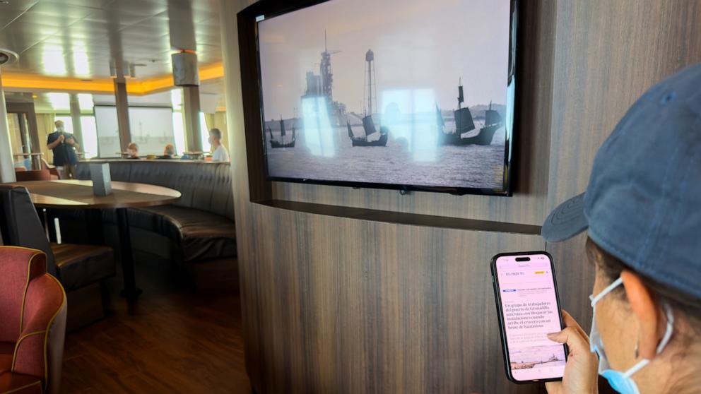 PHOTO: A passenger on the hantavirus-stricken cruise ship, MV Hondius, reads the news on his mobile phone during the voyage to Spain's port of Tenerife, May 6, 2026. 