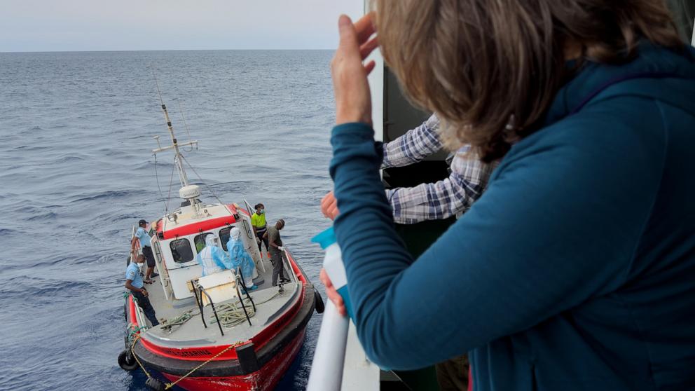 PHOTO: Passengers on the the hantavirus-stricken cruise ship, MV Hondius, watch epidemiologists board the boat in Praia, during their voyage to Spain's port of Tenerife, May 6, 2026.