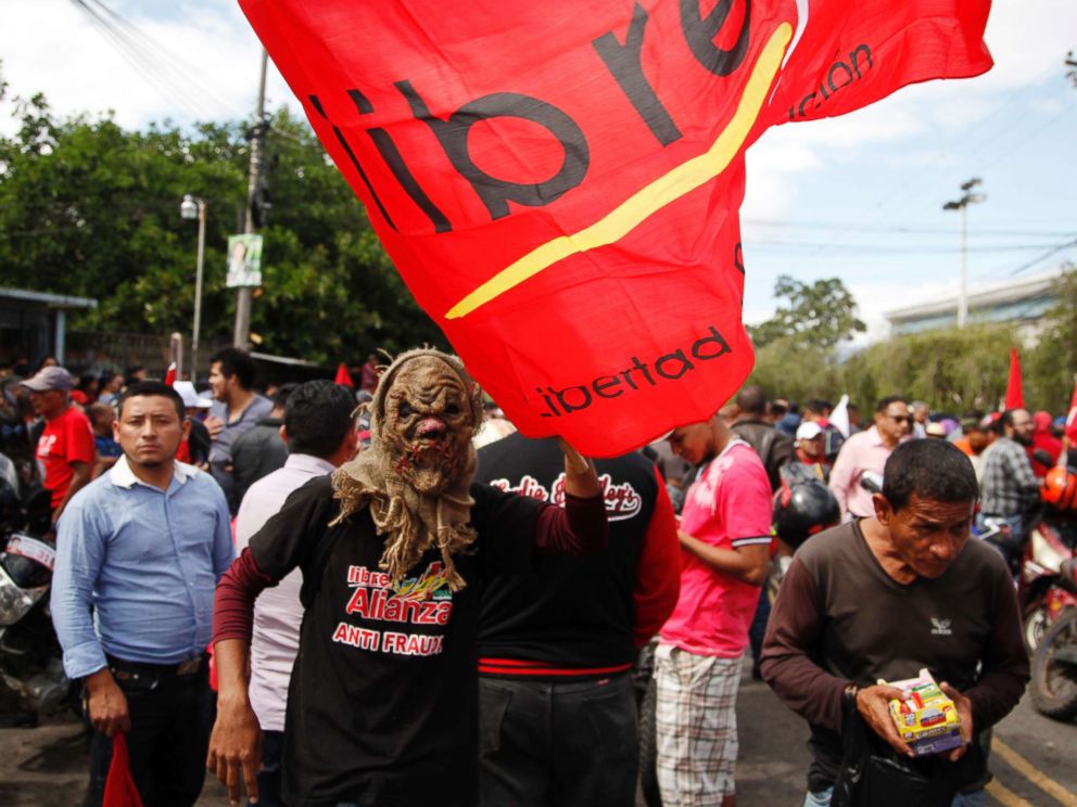 PHOTO: A supporter of Libre Alliance presidential candidate Salvador Nasralla wears a mask and holds a party banner during a protest march claiming electoral fraud, in Tegucigalpa, Honduras, Nov. 29, 2017.