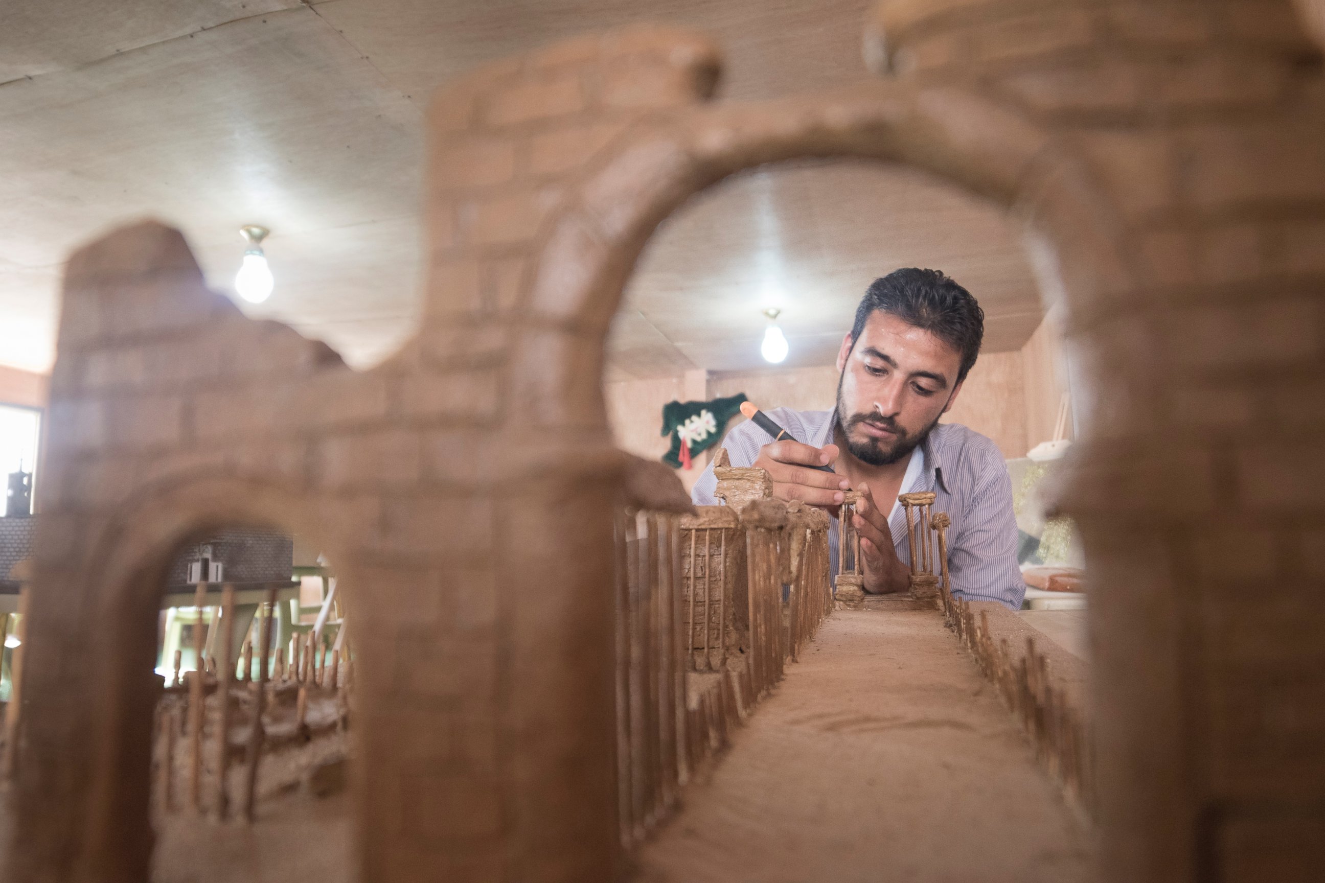 PHOTO: Mahmoud built his model of Palmyra using clay and wooden kebab skewers. Mahmoud hopes that by seeing the exhibition, residents at Zaatari will remain connected with the country and culture they have been forced to leave behind. 