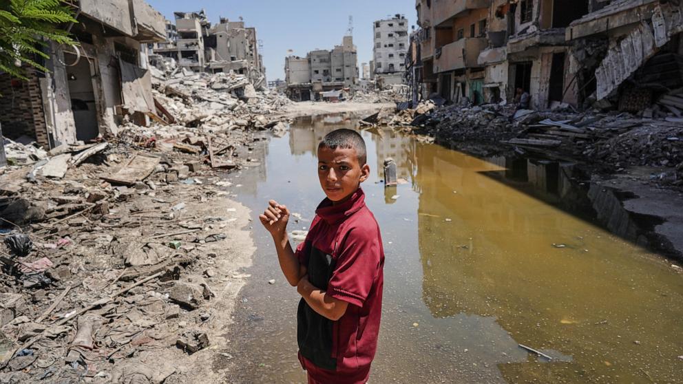 PHOTO: A Palestinian boy looks over as he stands on the rubble of buildings destroyed in previous Israel bombardment, on the edge of a pool of stagnant water in Khan Yunis in the southern Gaza Strip on July 19, 2024.