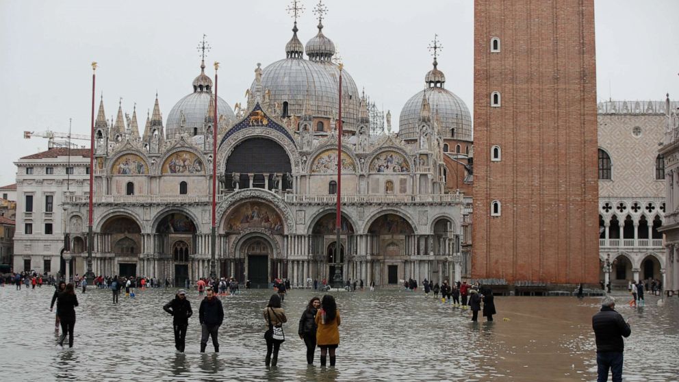 PHOTO: People wade through water in a flooded St. Mark's Square, in Venice, Wednesday, Nov. 13, 2019. The high-water mark hit 187 centimeters (74 inches) late Tuesday, Nov. 12, 2019, meaning more than 85% of the city was flooded. (AP Photo/Luca Bruno)