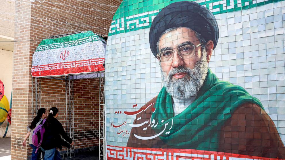 PHOTO: Women walk past a mural of Iranian Supreme Leader Ayatollah Mojtaba Khamenei along a street Tehran on May 6, 2026.