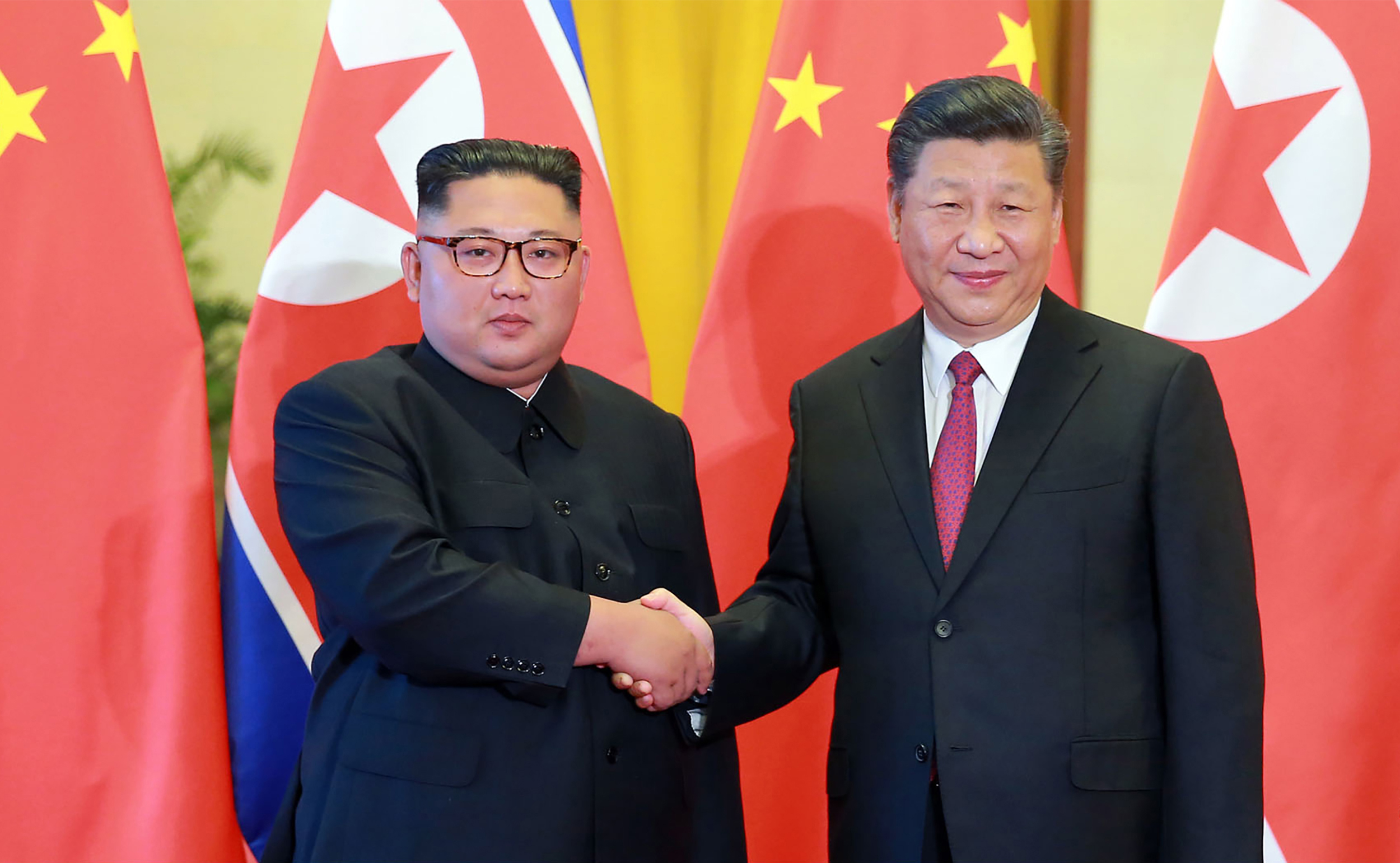 This picture taken on June 19, 2018 and released by North Korea's official Korean Central News Agency on June 20, 2018 shows North Korean leader Kim Jong Un, left, shaking hands with Chinese President Xi Jinping at the Great Hall of the People in Beijing.