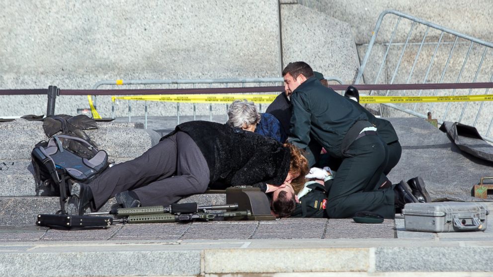 PHOTO: Police, bystanders and soldiers aid a fallen soldier at the War Memorial as police respond, Oct. 22, 2014 in Ottawa.
