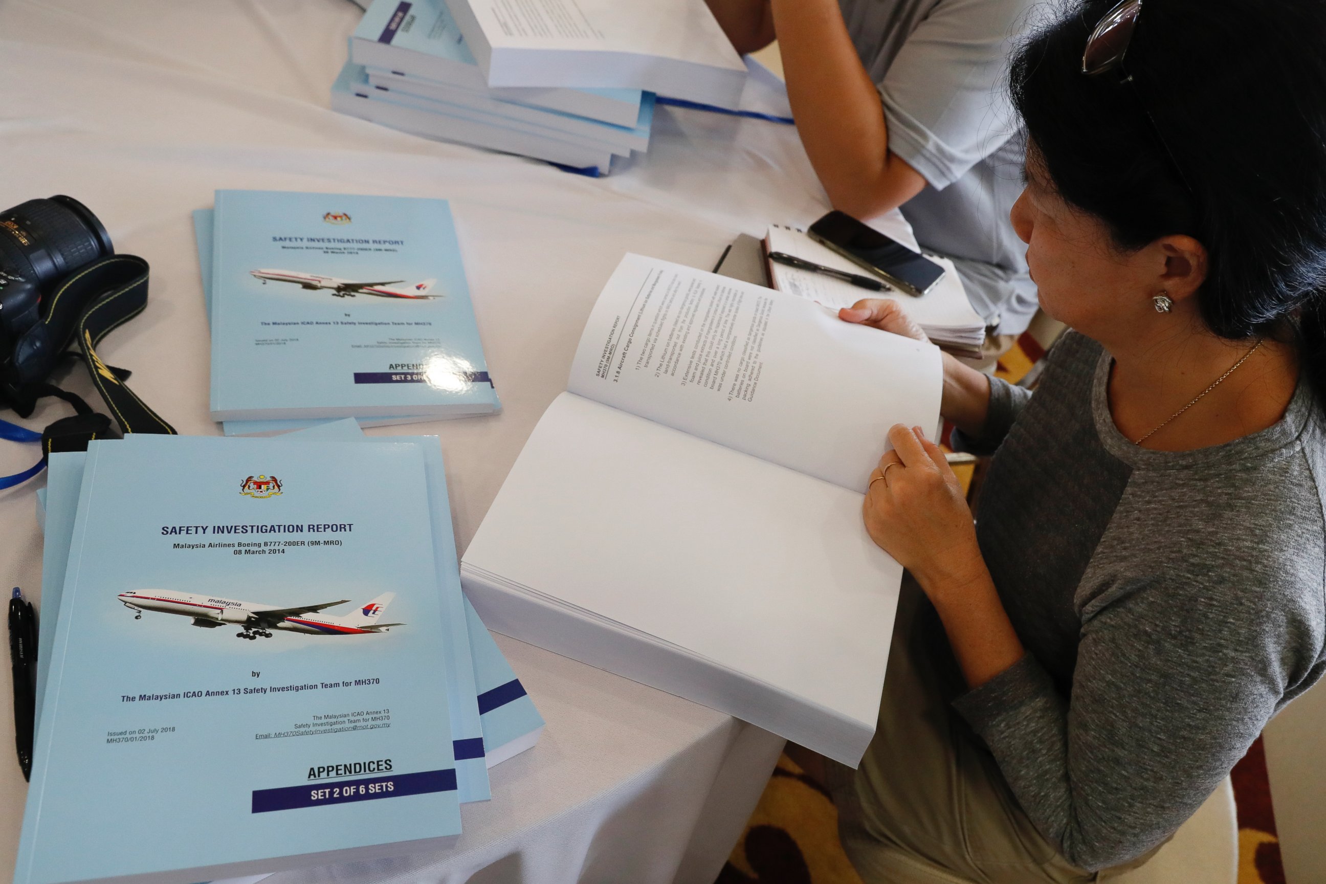 Copies of the final investigation report on missing flight MH370 are offered to the media in Putrajaya, Monday, July 30, 2018.