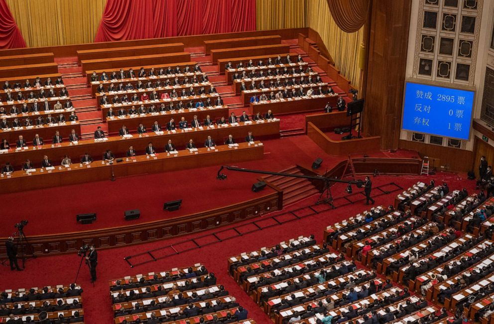 PHOTO: BEIJING, CHINA - MARCH 11: China's President Xi Jinping, center left, and lawmakers gather as the result of a vote in favor of a resolution to overhaul Hong Kong's electoral system is shown on a monitor.