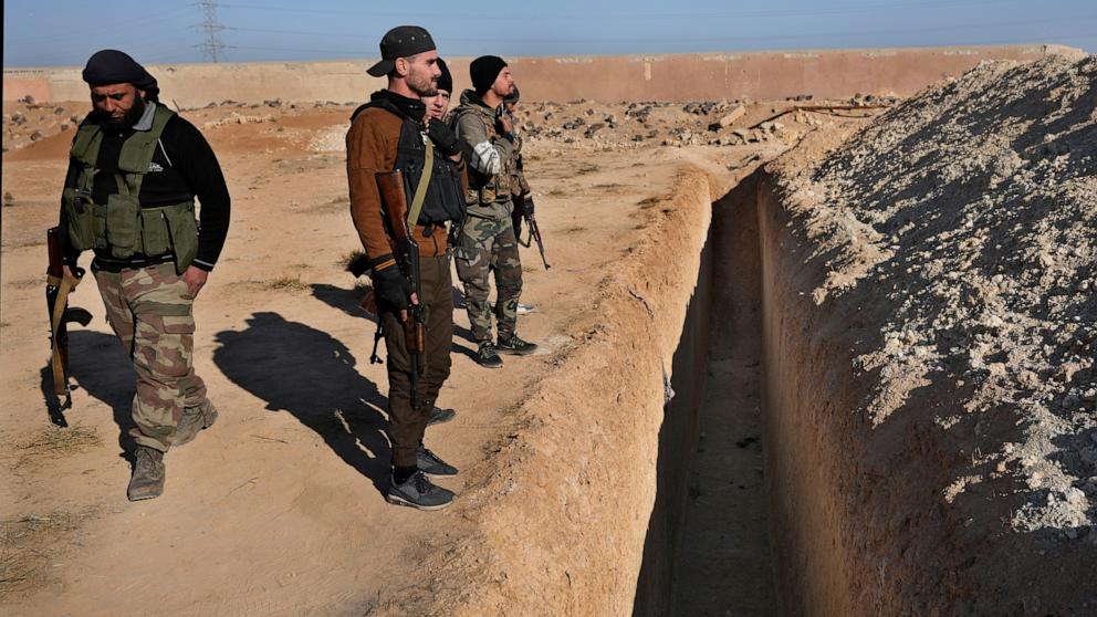 PHOTO: Syrian rebel fighters stand at a site identified as a mass grave for detainees killed under rule of former President Bashar Assad in Najha, south of Damascus, on Dec. 17, 2024.