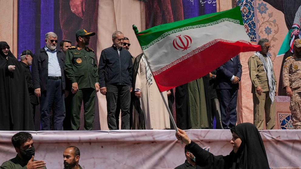PHOTO: Iranian President Masoud Pezeshkian and other officials watch as a woman waves an Iranian flag during the state-organized parade in Tehran, Iran, on Sept. 18, 2026.