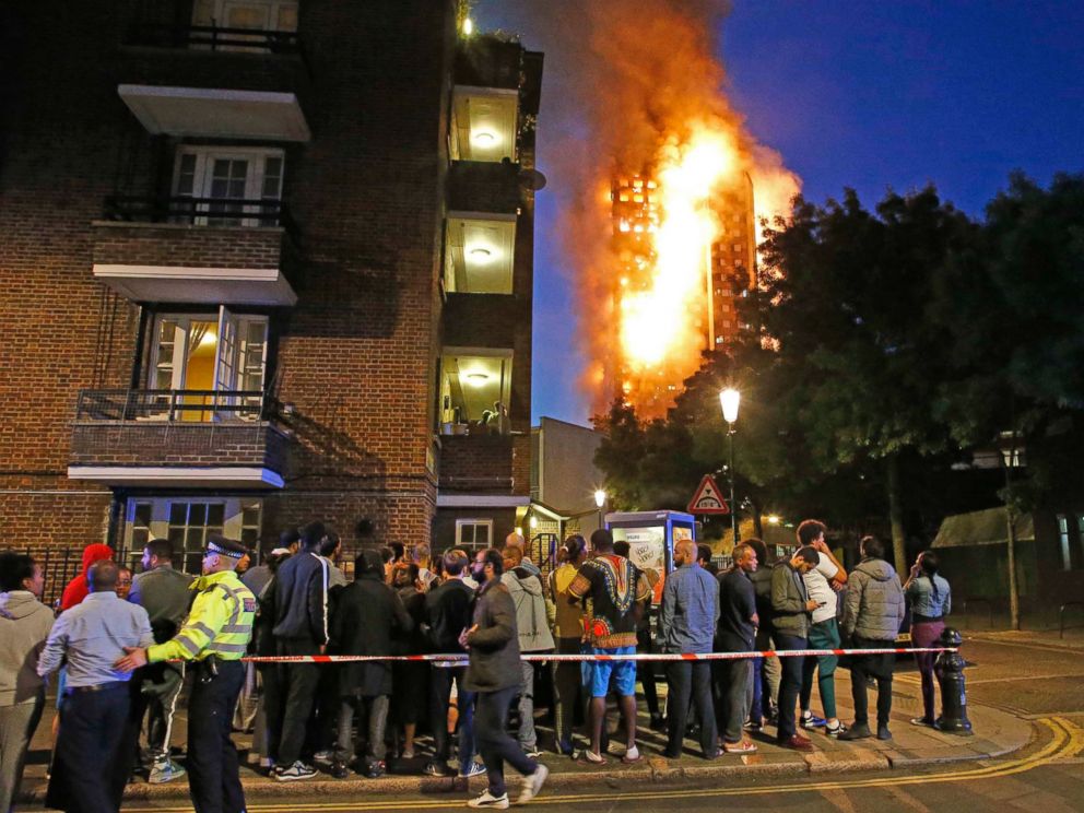 PHOTO: People watch the Grenfell Tower fire as it burns in the early hours of June 14, 2017 in London.