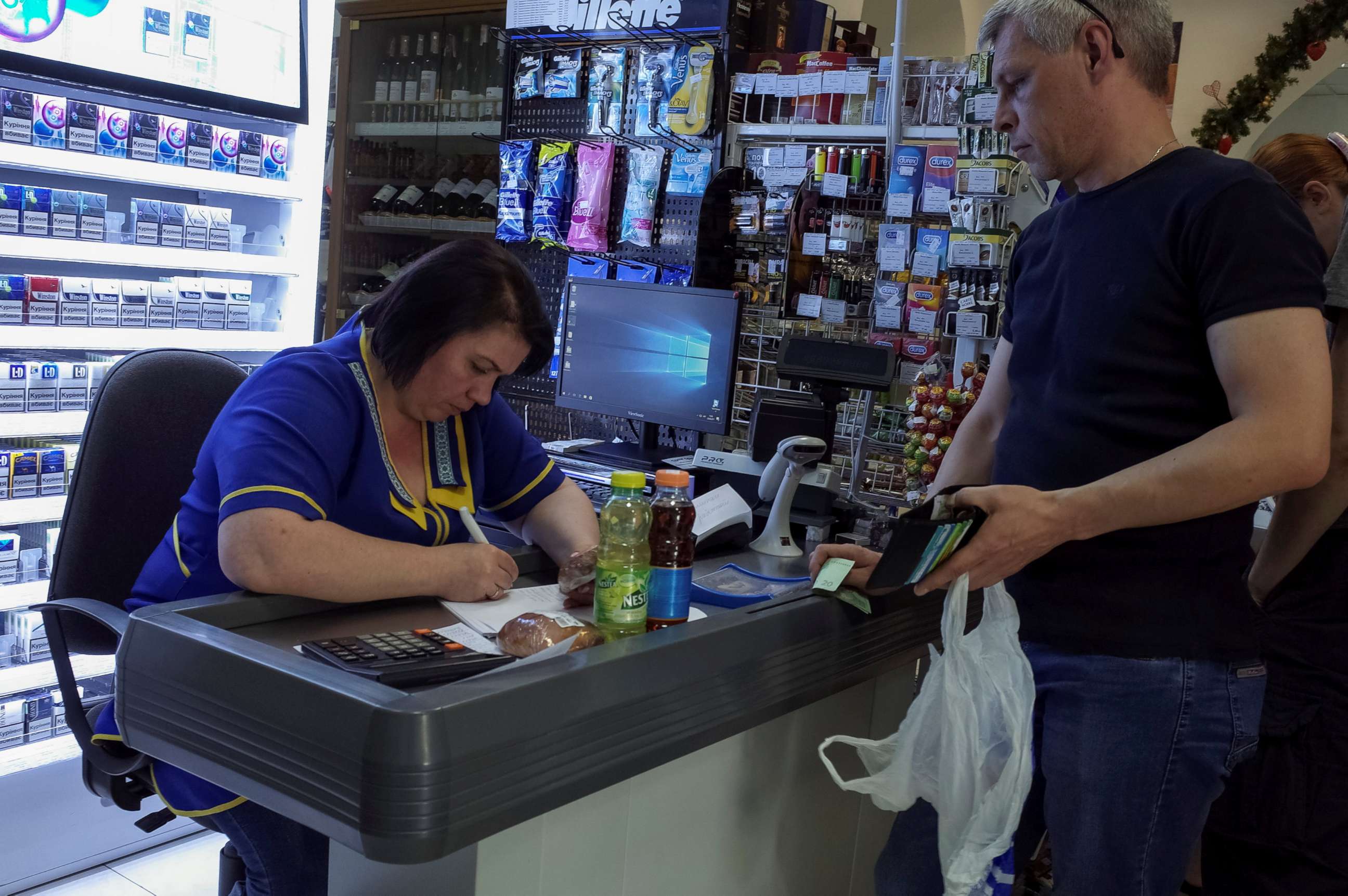 PHOTO: A customer at a store in Kiev, Ukraine, waits while a cashier writes out a purchase receipt for store records, as many business have turned off their digital cash registers after cases of cyber attacks on business, June 28, 2017.