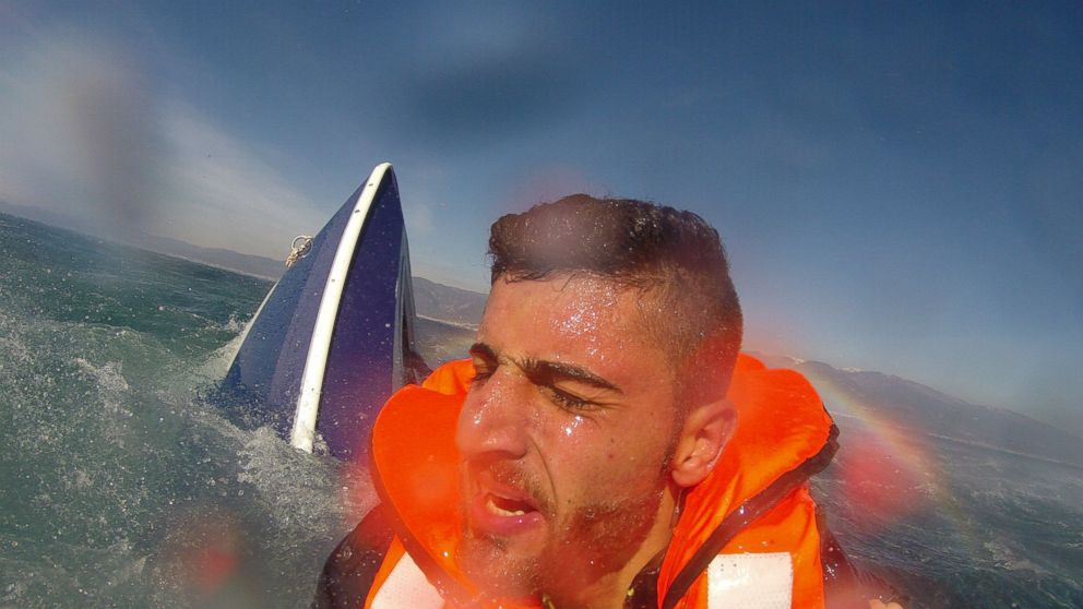 PHOTO: A migrant, identified as 20-year old Pelen Hussein from Syria, with a capsized boat in the background, as he was rescued by a member of the Turkish Coast Guard Air Command in the Aegean Sea off the waters of Edremit bay, Turkey Feb. 8, 2016. 