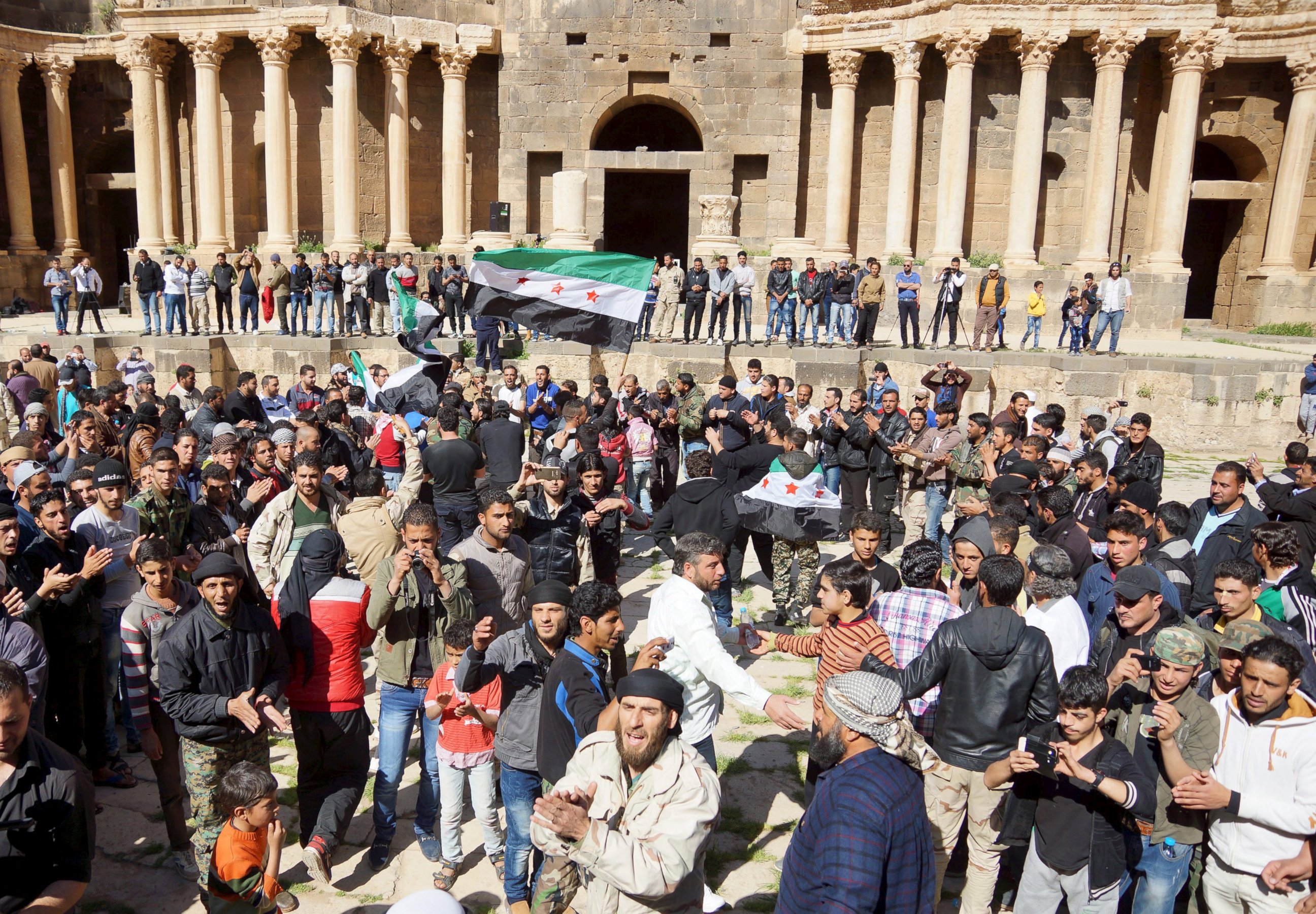 PHOTO: Protesters carry opposition flags and chant slogans during an anti-government protest inside a 2nd century Roman amphitheater in the historic Syrian southern town of Bosra al-Sham, in Deraa, Syria, March 4, 2016. 